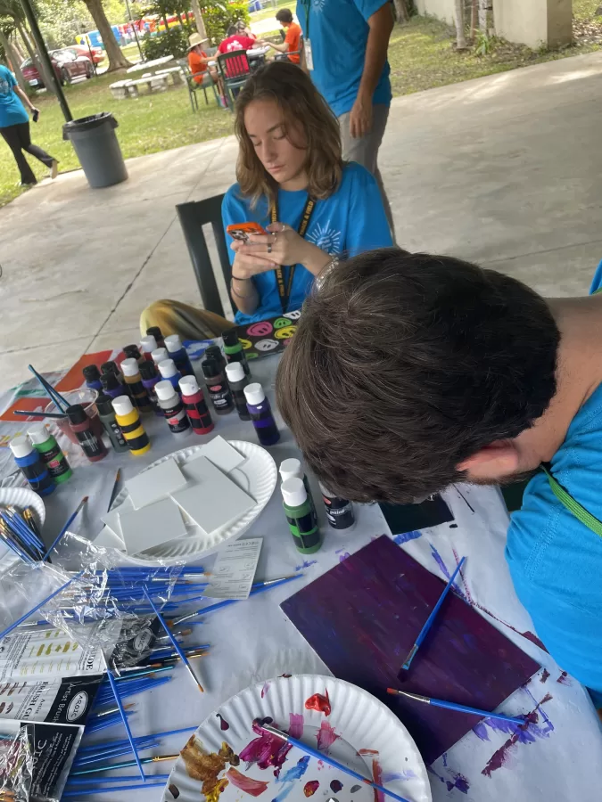 Junior Colette Finley with Mr. Tim Gamwell at the painting station located in the pavilion during Don Bosco Day. There were so many games and activities to do.