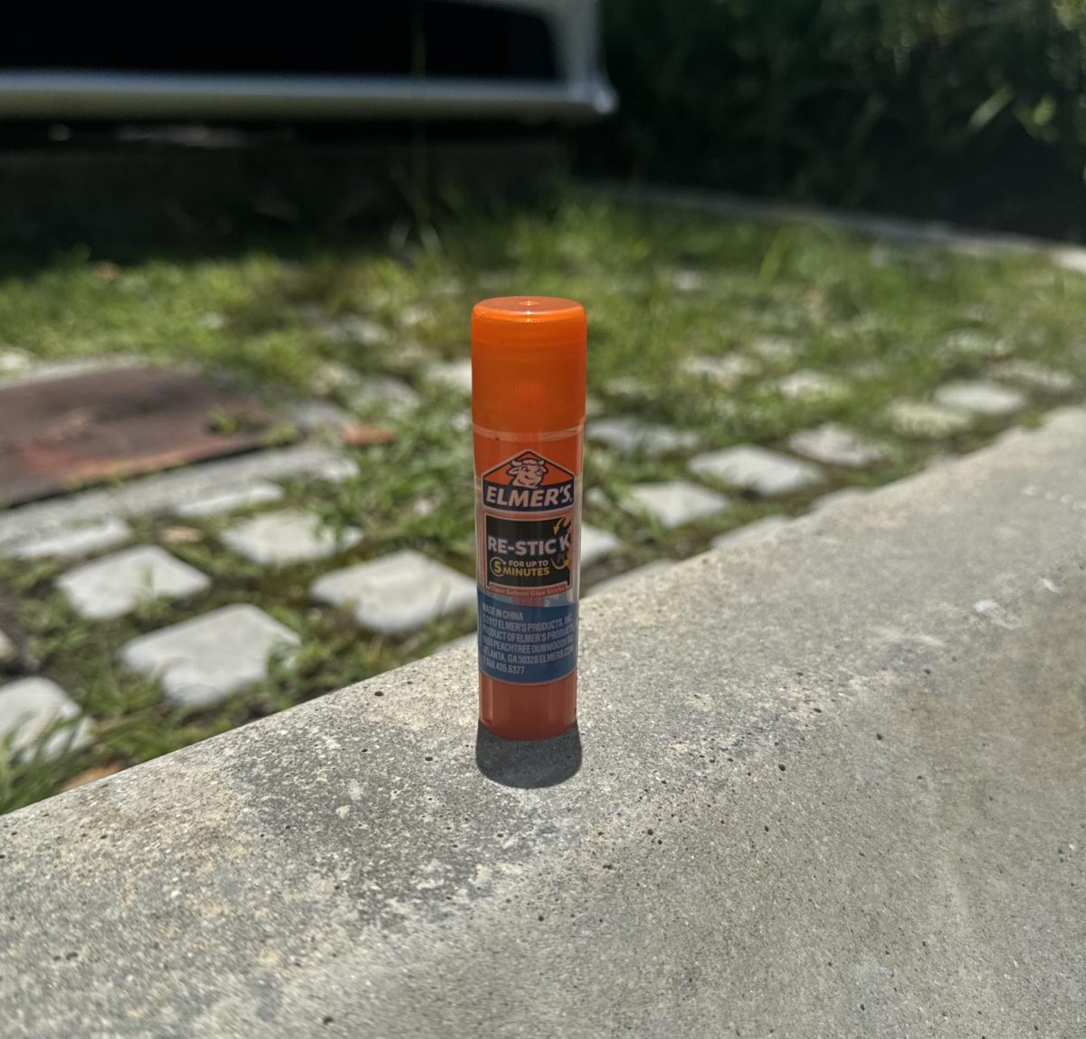 An Elmer’s glue stick rests on a ledge in it natural habitat, a school campus.
