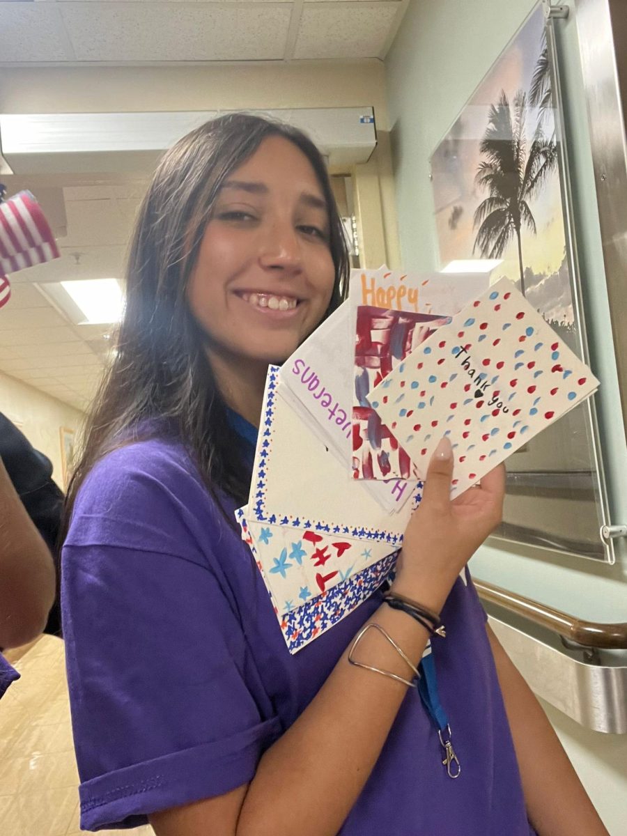 Showcasing one of the many greeting cards created by club members, this ILS volunteer displays a handful.