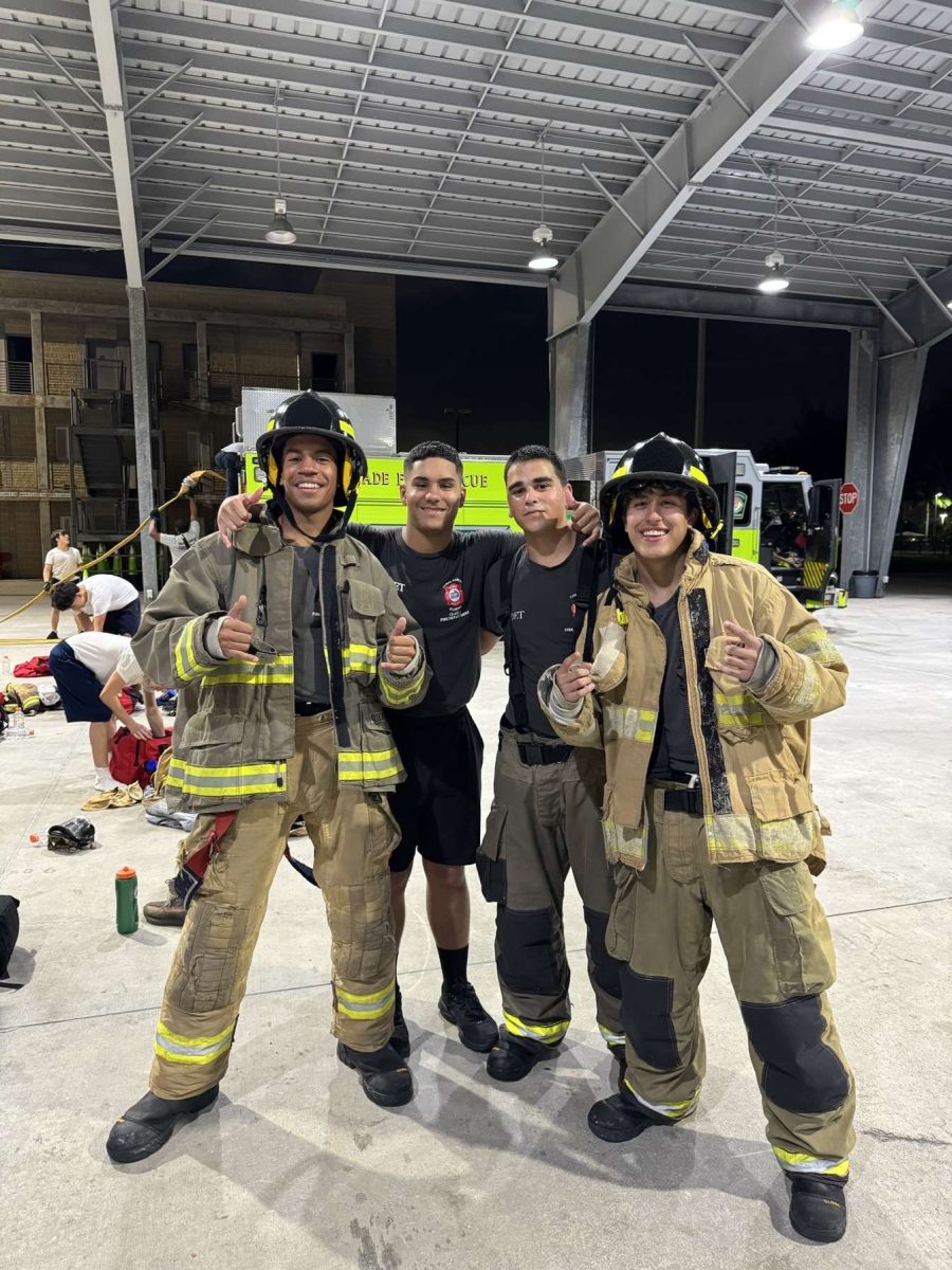 Cadet Hector Gutierrez stands proudly alongside two of his instructors and a fellow cadet