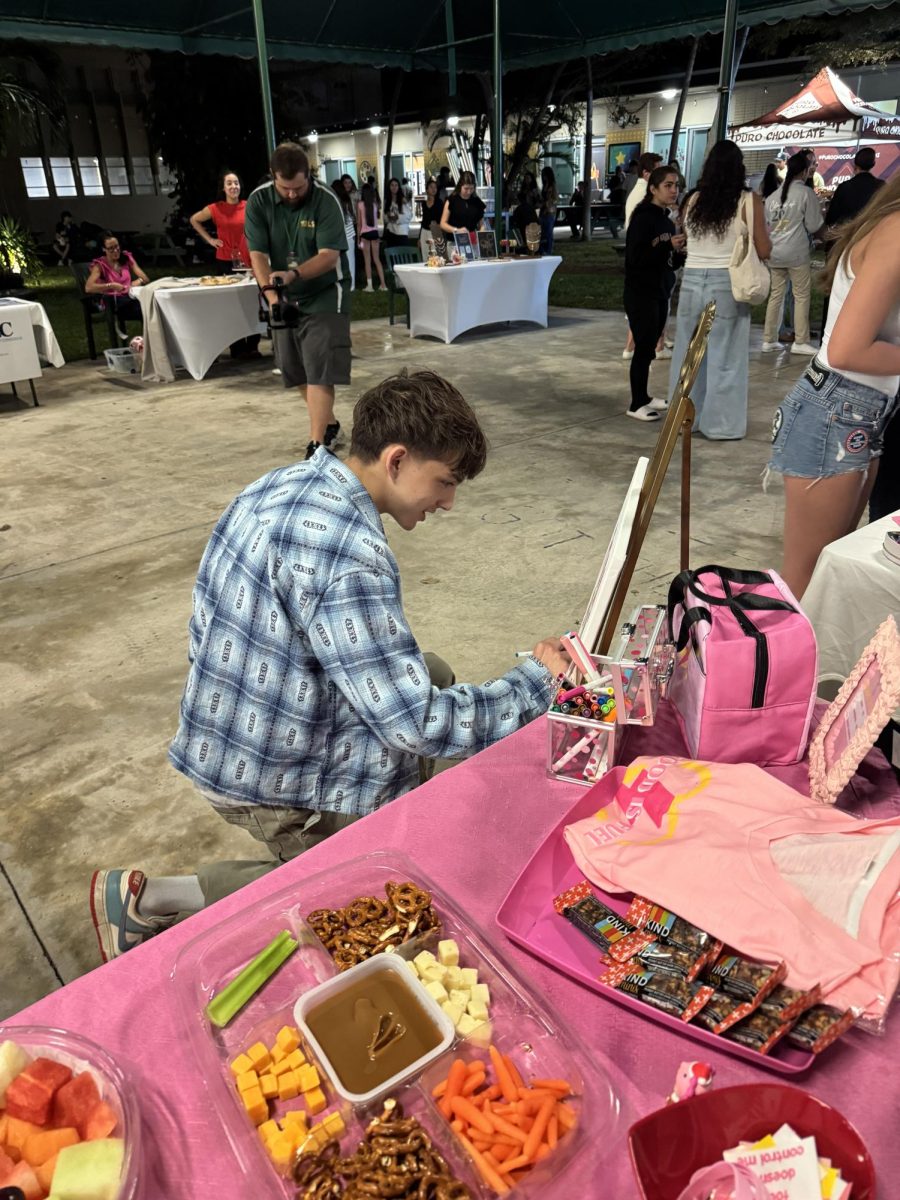 A student at Art Walk engages in Food Is Fuel’s vendor stand.