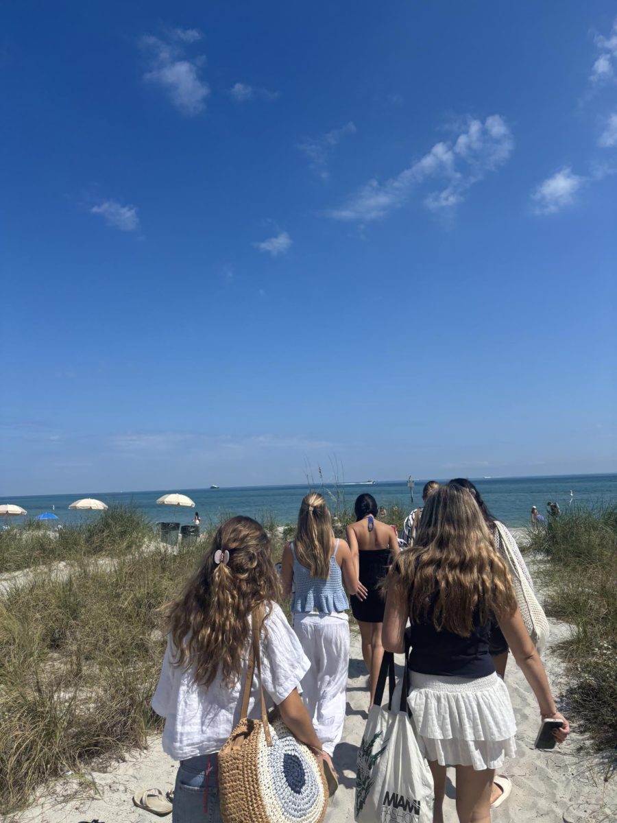 A group of girls walking onto the beach, enjoying the sun. 