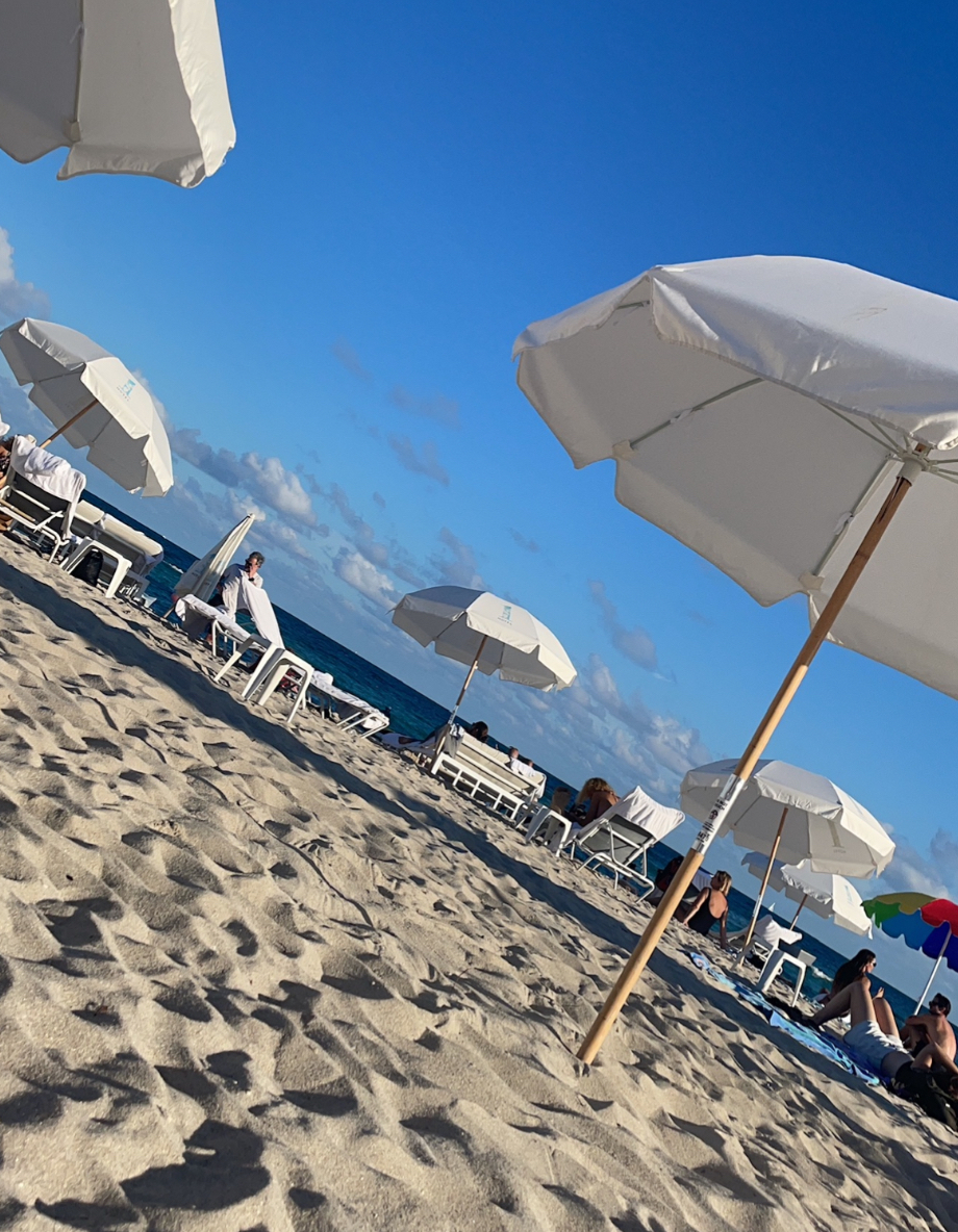 Umbrellas and beach chairs dot a stretch of Miami Beach pictured on a partially sunny day.