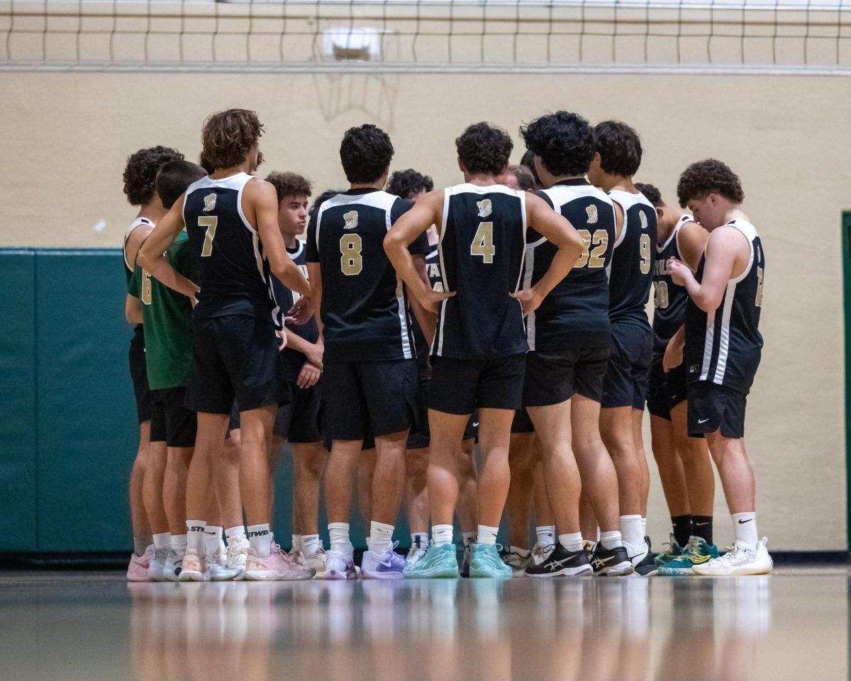 Boys' Volleyball team members huddle before a play at the ILS gym.