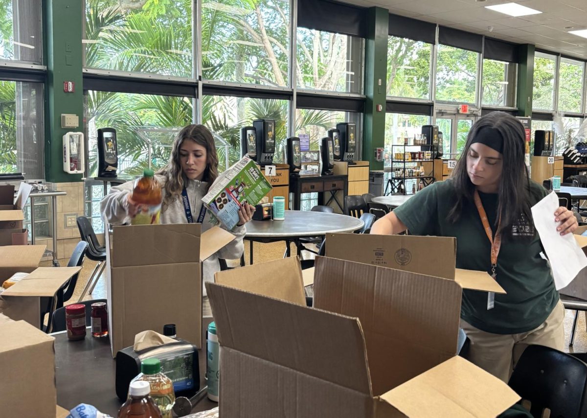 Junior Mayte Tassich and friend pack food into boxes. 