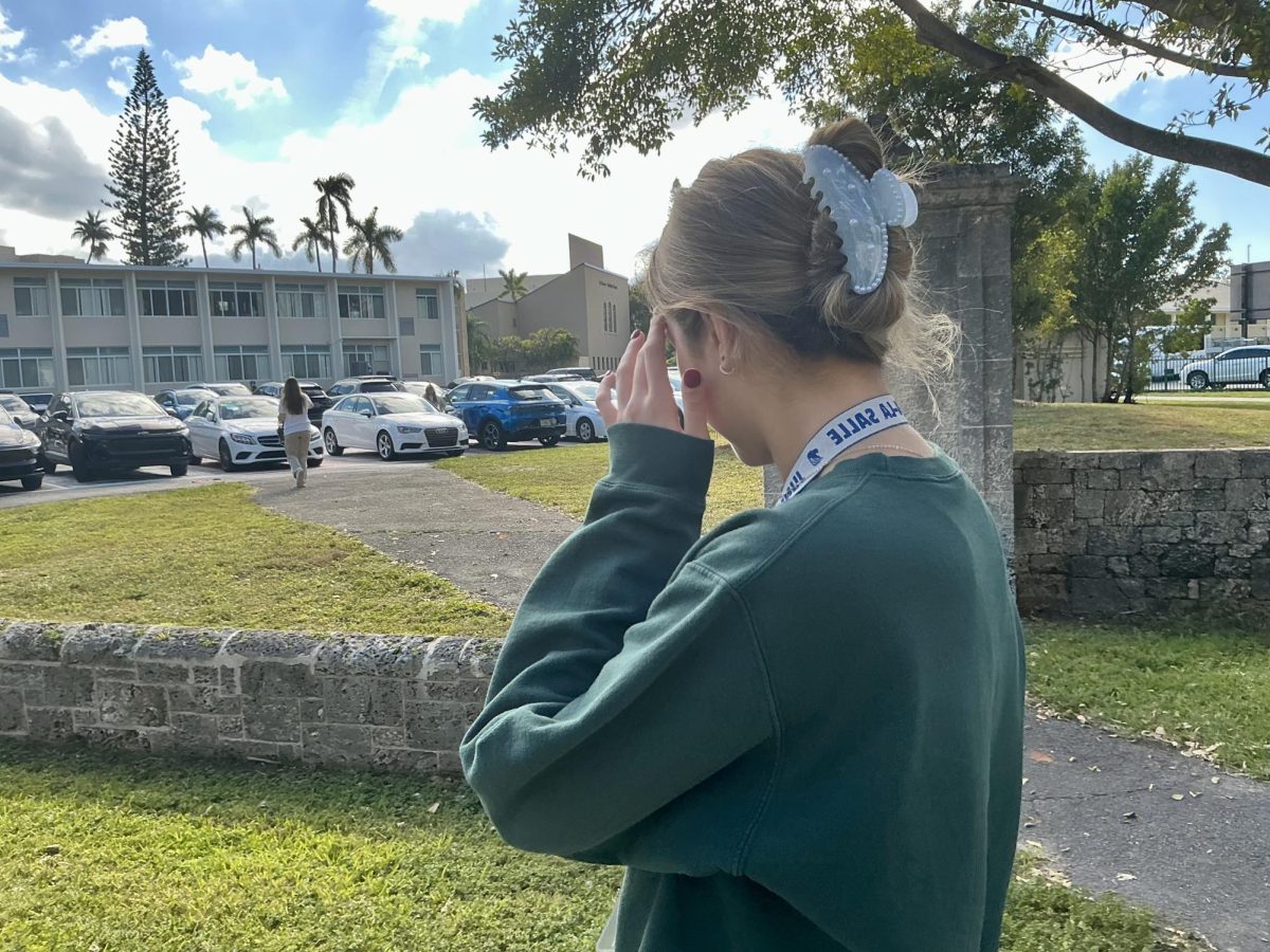 Student Luciana Gadala-Maria, Junior, adjusts her hair near the parking lot as she prepares to head to her next class.
