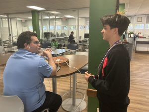 Facing a tough assignment, Samuel Barrios asks Mr. Michael Carrey for help with his Geometry homework. This shot captures the moment Samuel takes charge of his learning despite the challenge of his injury.