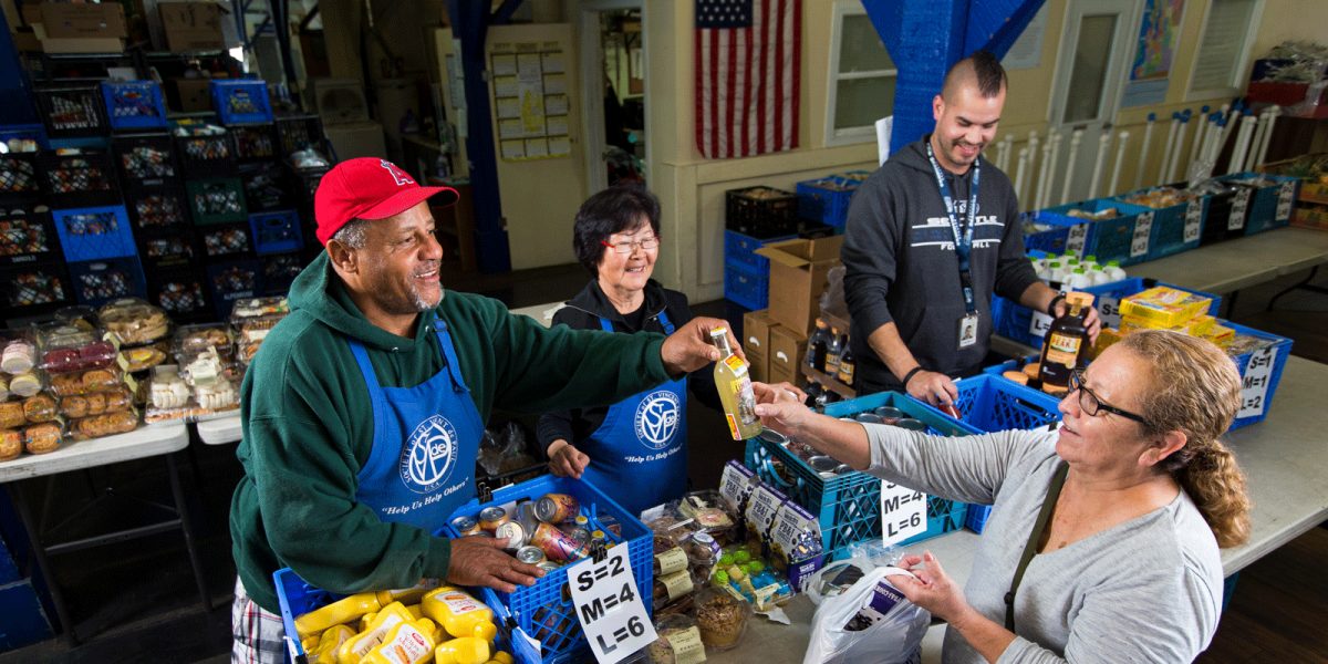 Volunteers with the Society of St. Vincent de Paul Miami District sort and package donated food items, preparing them for distribution to local families in need.