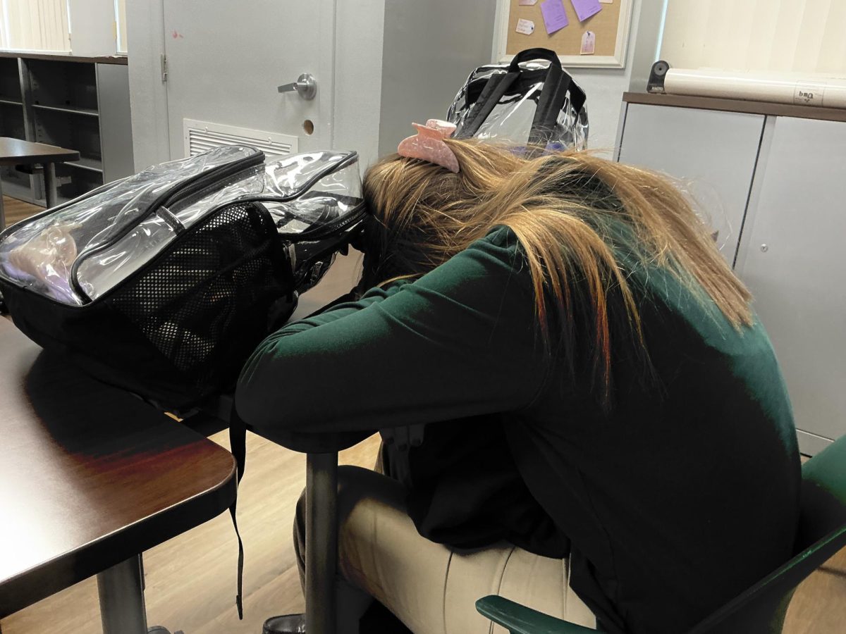Student, rests at her desk during a break. This shot captures a rare moment of stillness and personal space in a busy classroom.