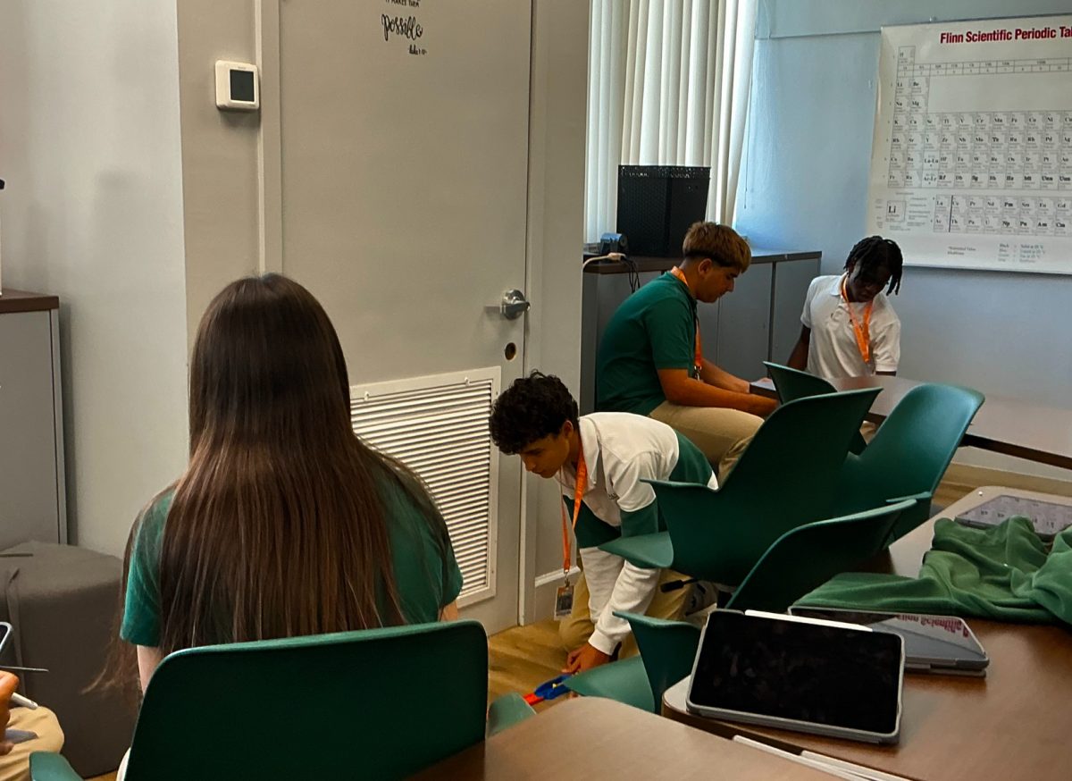focuses on his work near the floor. The full shot shows how students find their own quiet corners to concentrate, even in shared spaces