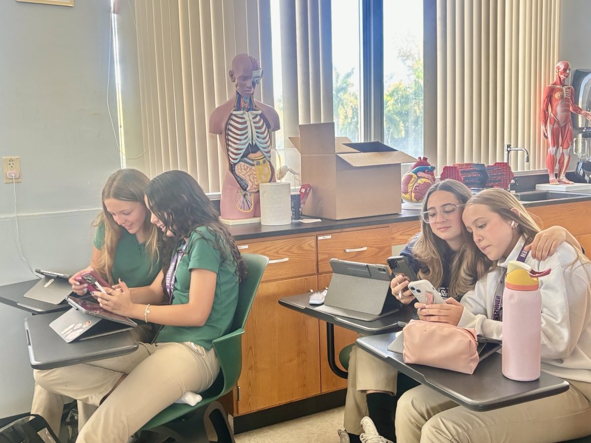 Valentina Orozco, Violet Morse, Marina Trinidade Henrique, and Julia Dias sit side by side on their phones, engaging with political content, and conversing about what they learn. 
