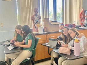 Valentina Orozco, Violet Morse, Marina Trinidade Henrique, and Julia Dias sit side by side on their phones, engaging with political content, and conversing about what they learn. 