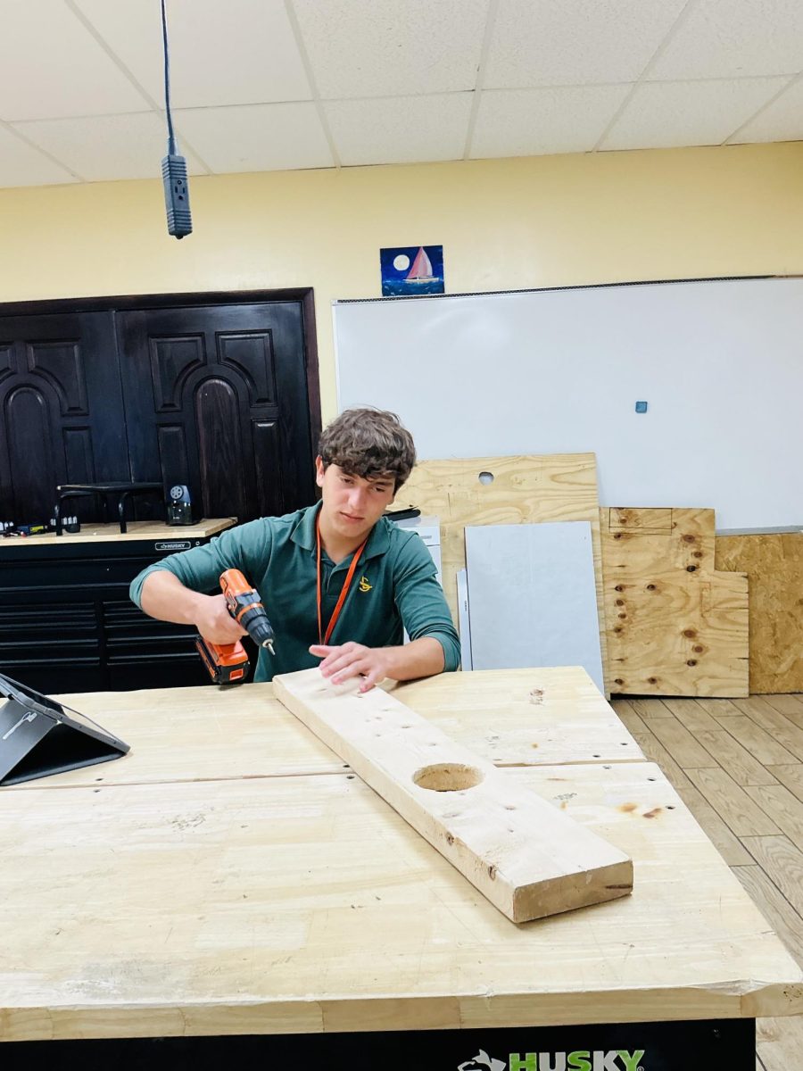 Sophomore Aquiles Maduro learns how to use a drill on a plank of wood during his robotics class during E block at ILS.