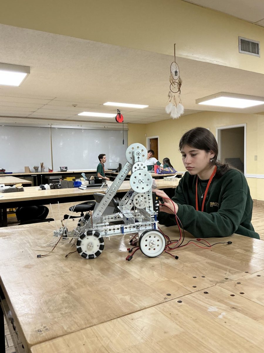 Designing and testing her newest engineering project, Sophomore Maria Martinez, connects power cables to energize her robotic invention. 