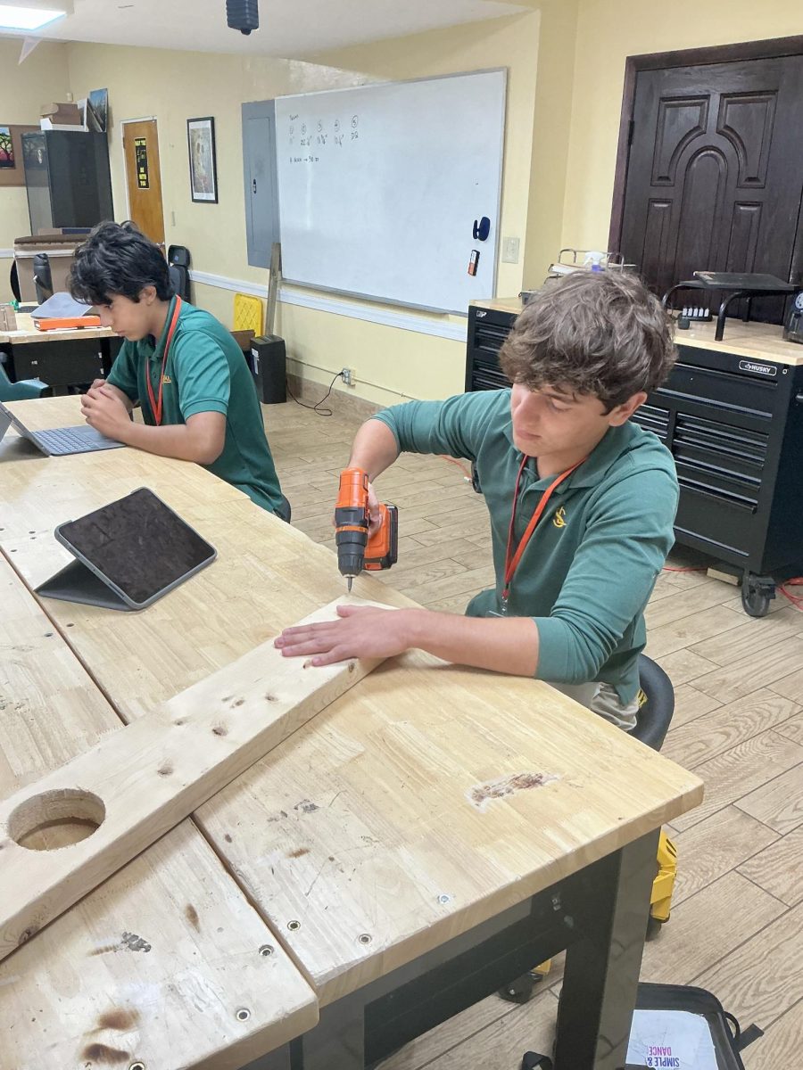 Sophomore, Aquiles Maduro utilizes drill to create a wooden plank in Youth Center 