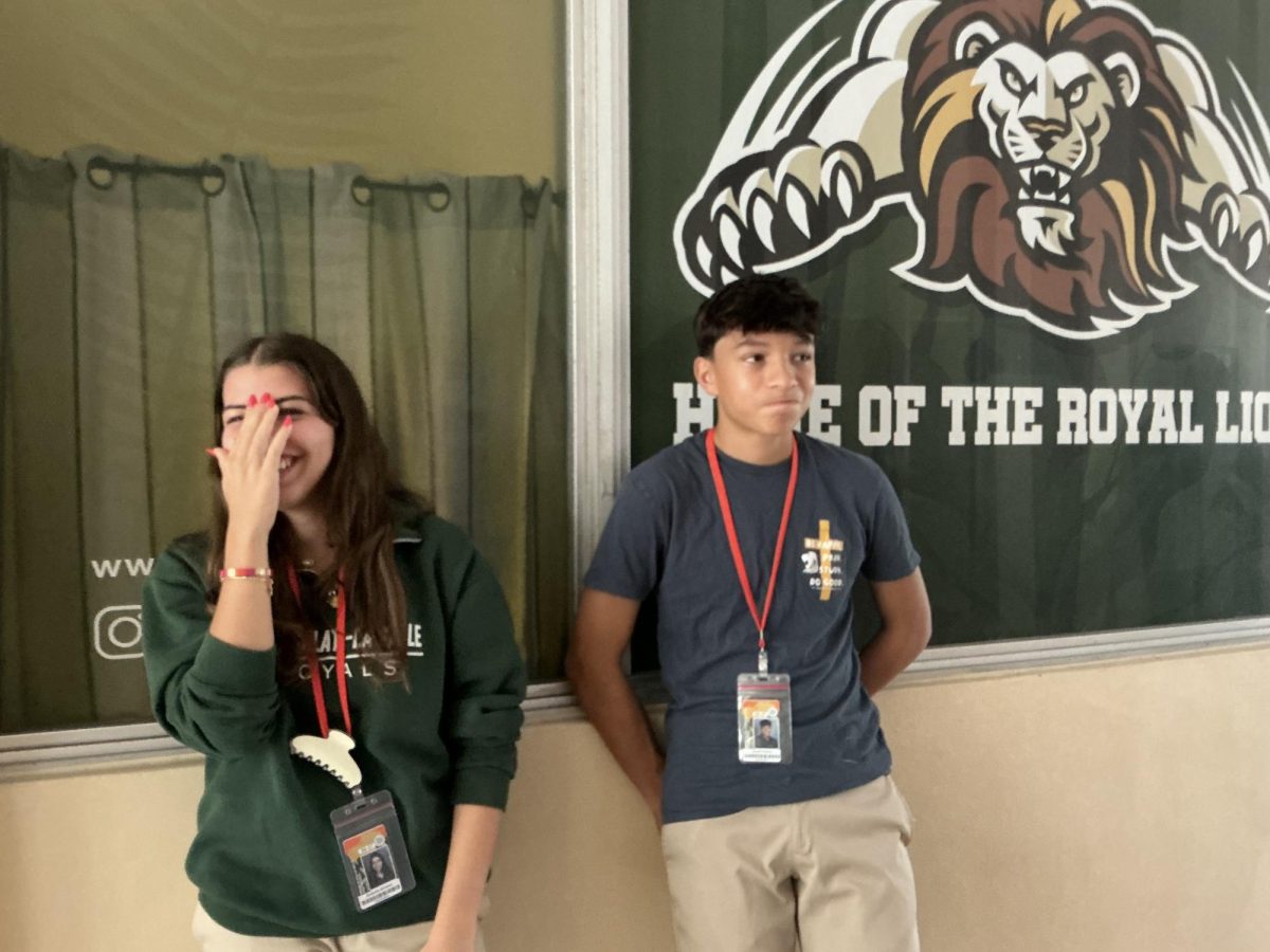 Sophmores Isabella Alvarez and Jacob Fleitas show their school spirit in front of La Salle’s lion mascot banner.