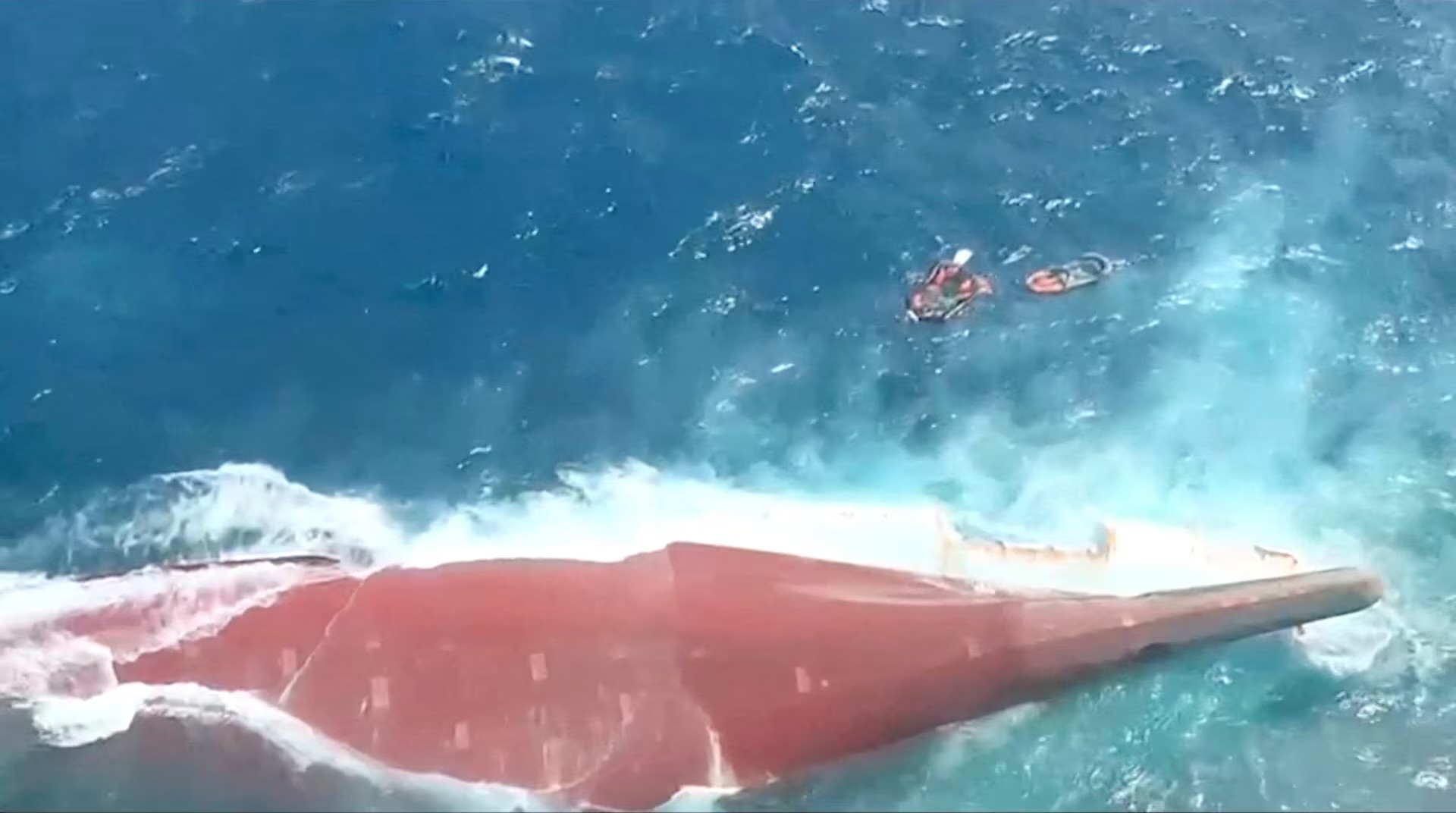 The overturned ferry rests in the Java Sea as waves surround the vessel.