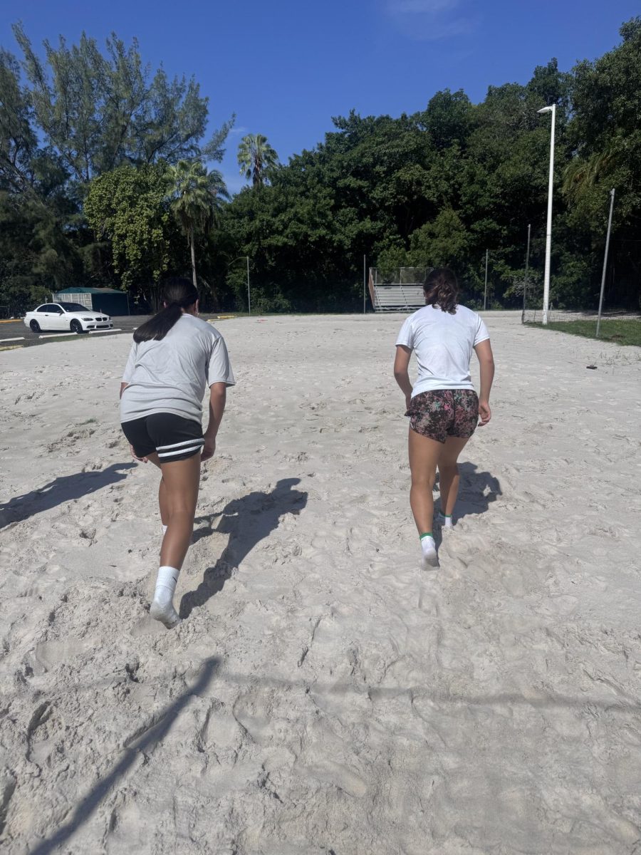 Juniors Stefania Kyriazis and Myah Taher get ready to run up and back during a sand workout on the beach volleyball court after school under blazing heat.