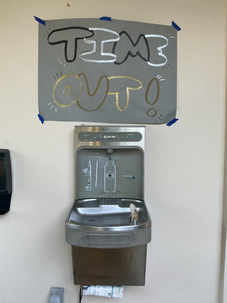 A water fountain is seen with the time out sign above.