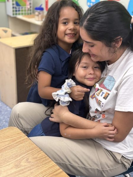 Senior Zoe Pazos, a member of the SALTT executive board, shares a moment with two children in a classroom.