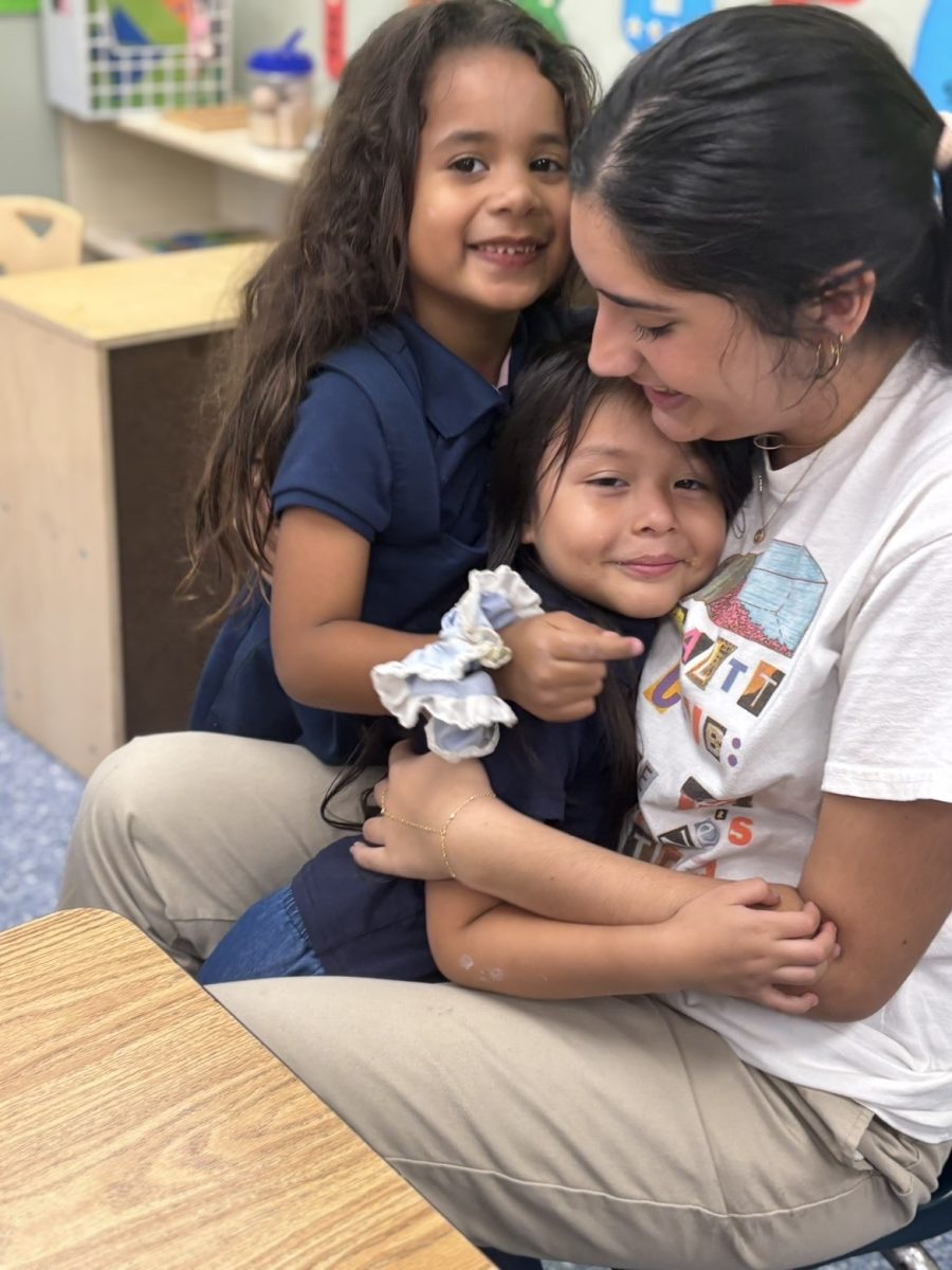 Senior Zoe Pazos, a member of the SALTT executive board, shares a moment with two children in a classroom.