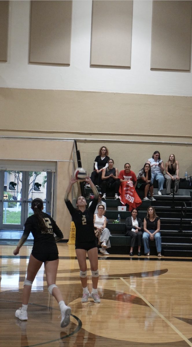 With complete focus on the court, player #2 sets up a scoring opportunity in front of the spectator stands during a volleyball game.